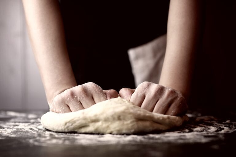 Person's two hands on dough demonstrating how to make truffle pizza