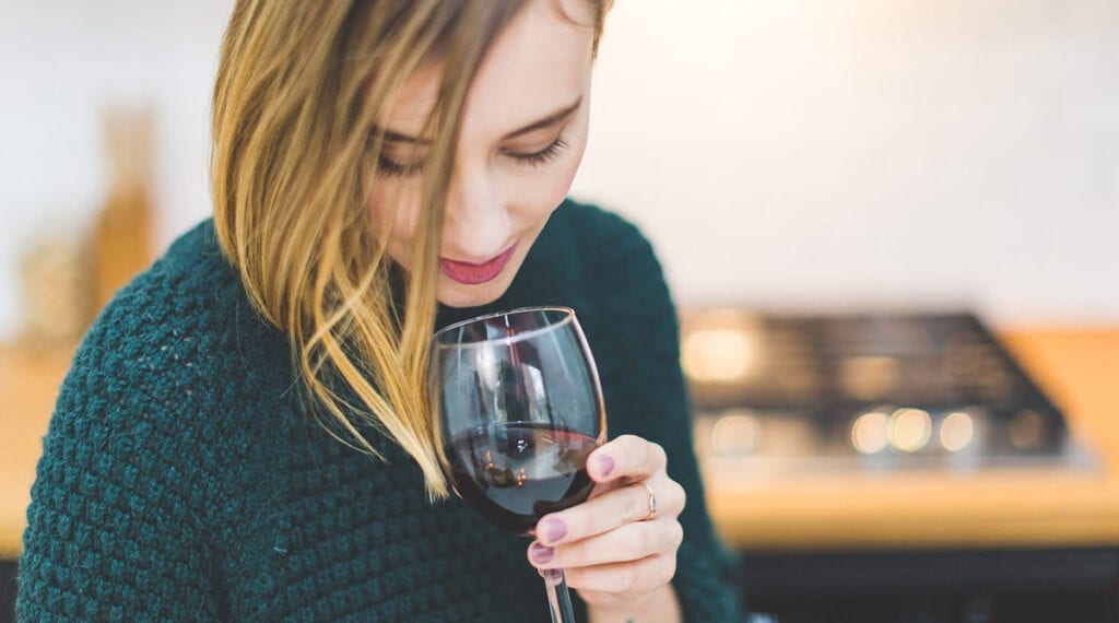 Young woman smelling red wine from a glass