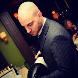 Sommelier Todd Lipman pouring a large bottle of wine in a restaurant