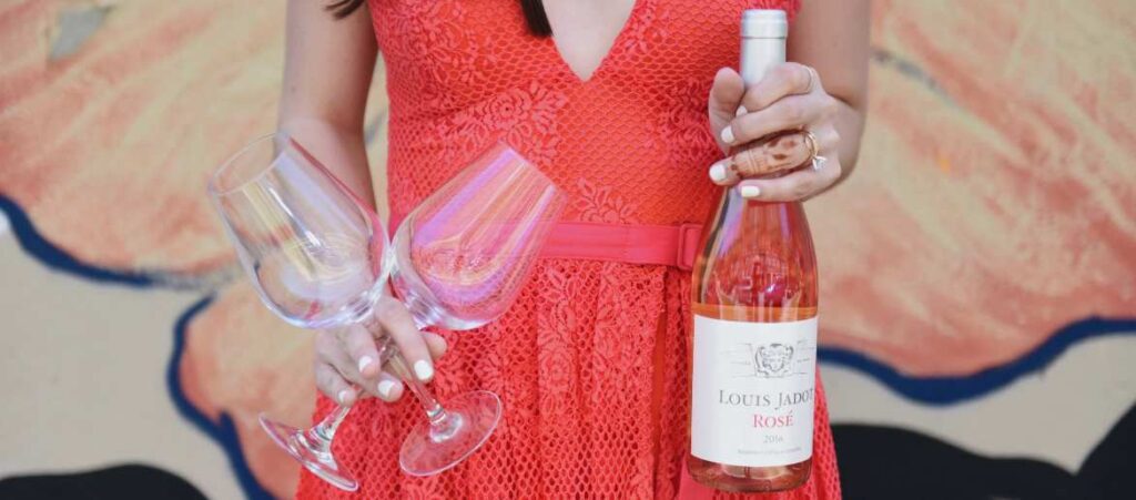 Girl holding two glasses and bottle of rose wine