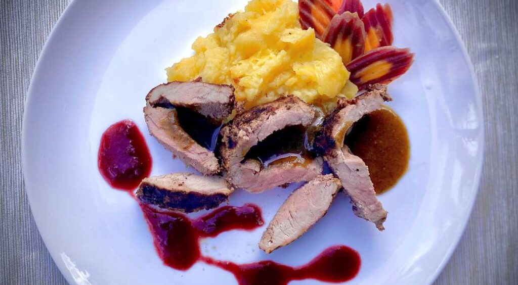 Plating pork with walnut tarragon pesto and strawberry red wine sauce