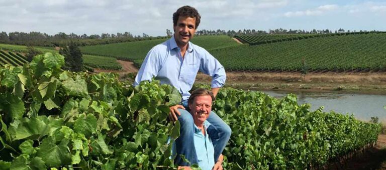 Aurelio Montes Jr. sitting on top of the shoulders of his father Aurelio Montes Sr. in the middle of a vineyard in Chile