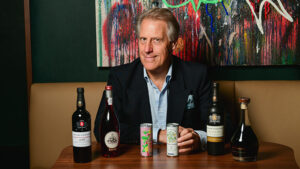 Adrian Bridge sitting at a table with four bottles of Port wine